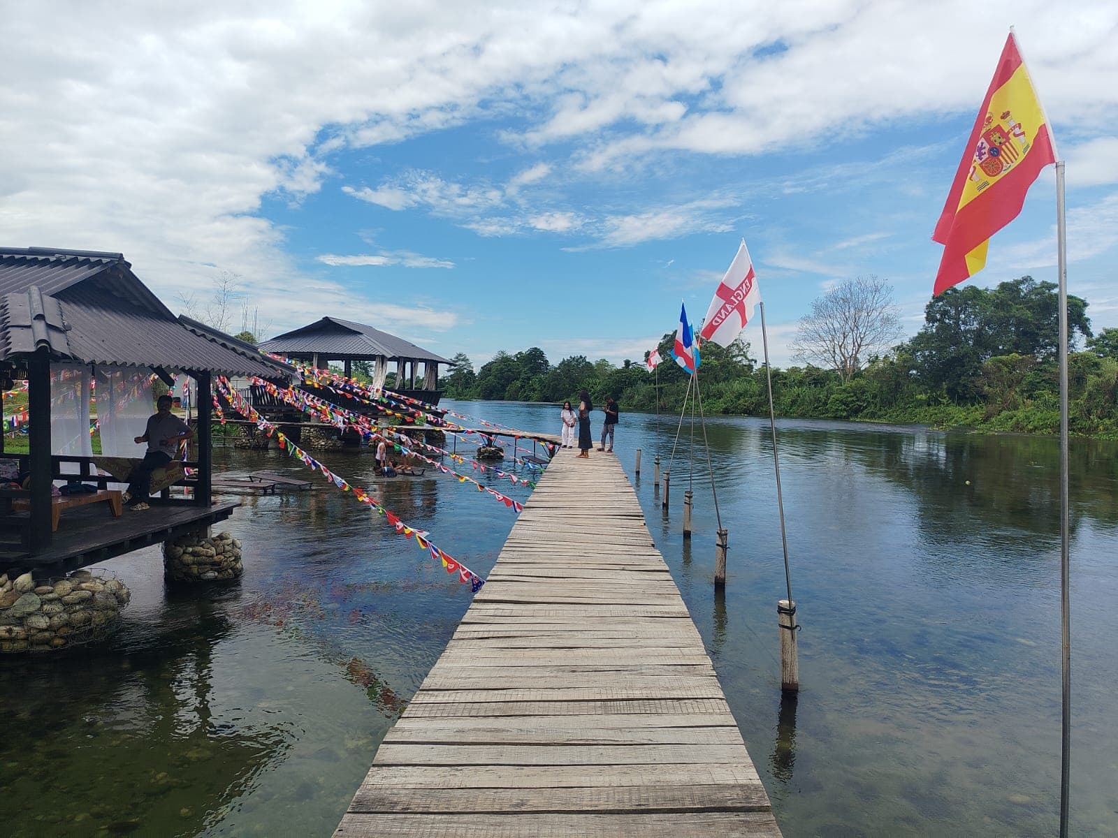 Wooden walkway beside a lake decorated with colourful flags