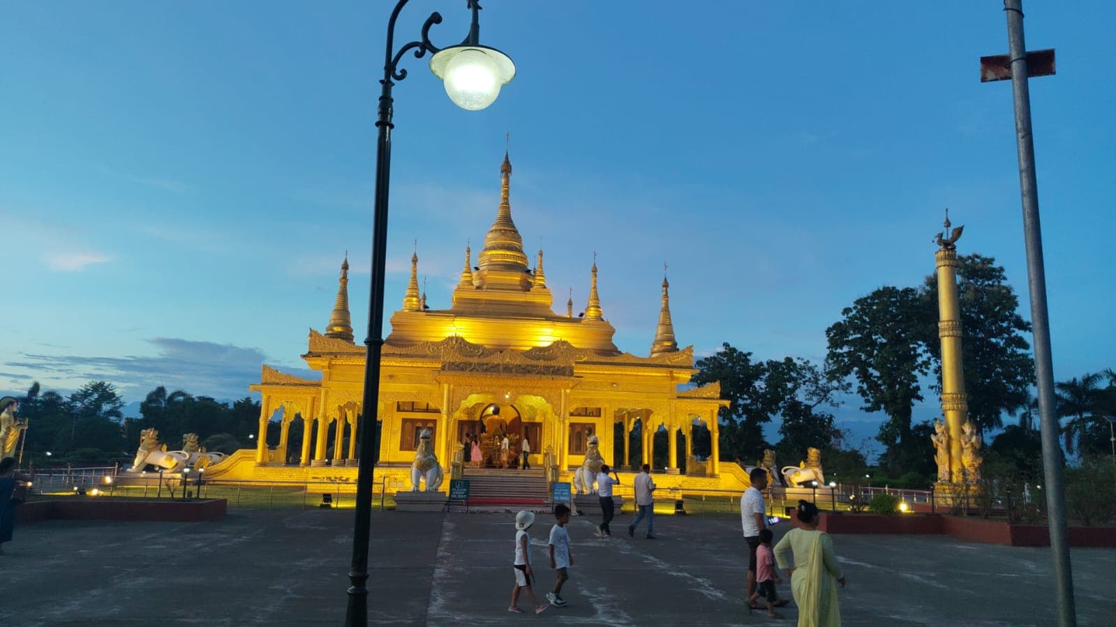 Illuminated golden temple framed by trees and a streetlight