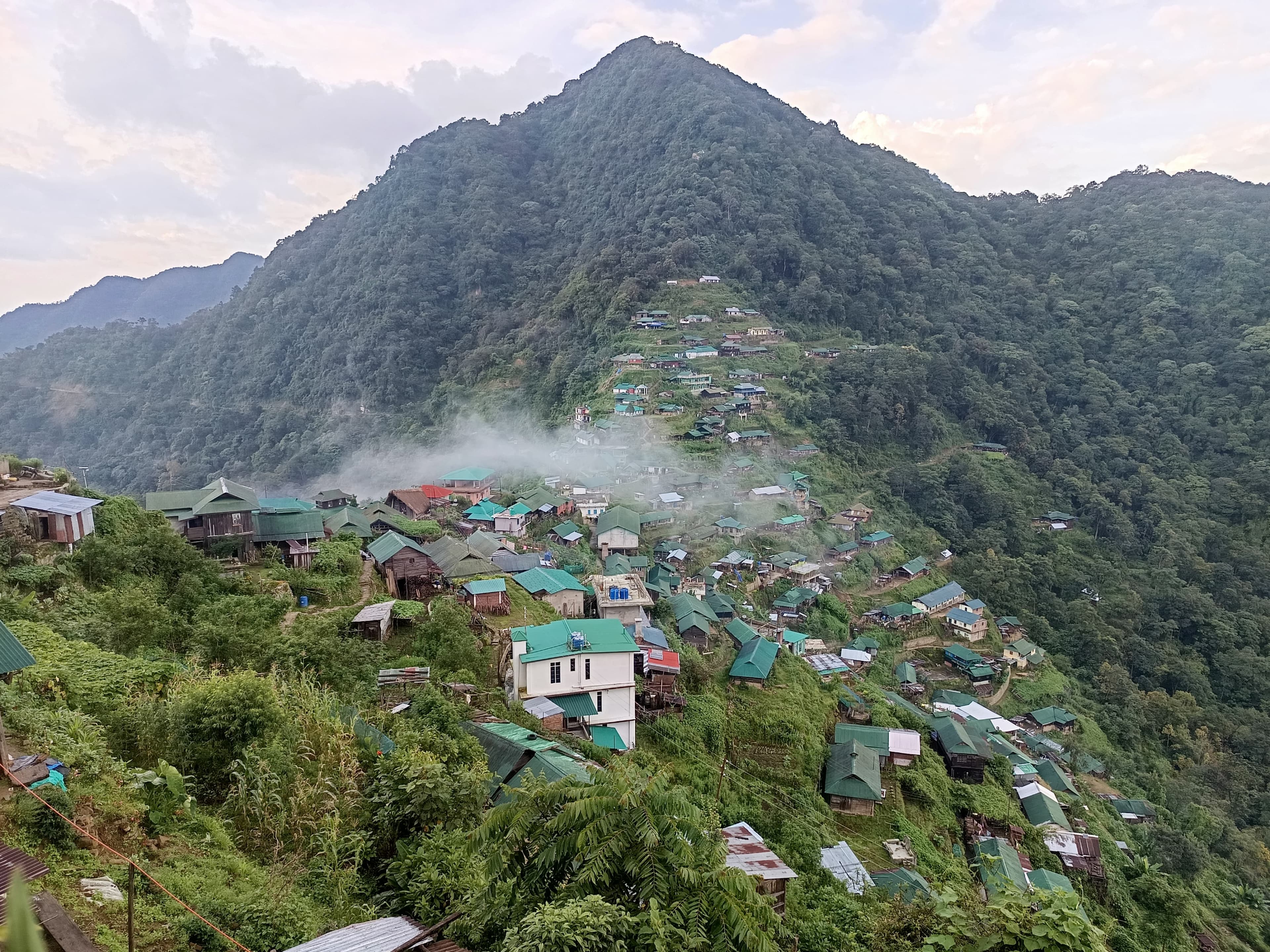 Houses in Benreu beneath a steep forested mountain