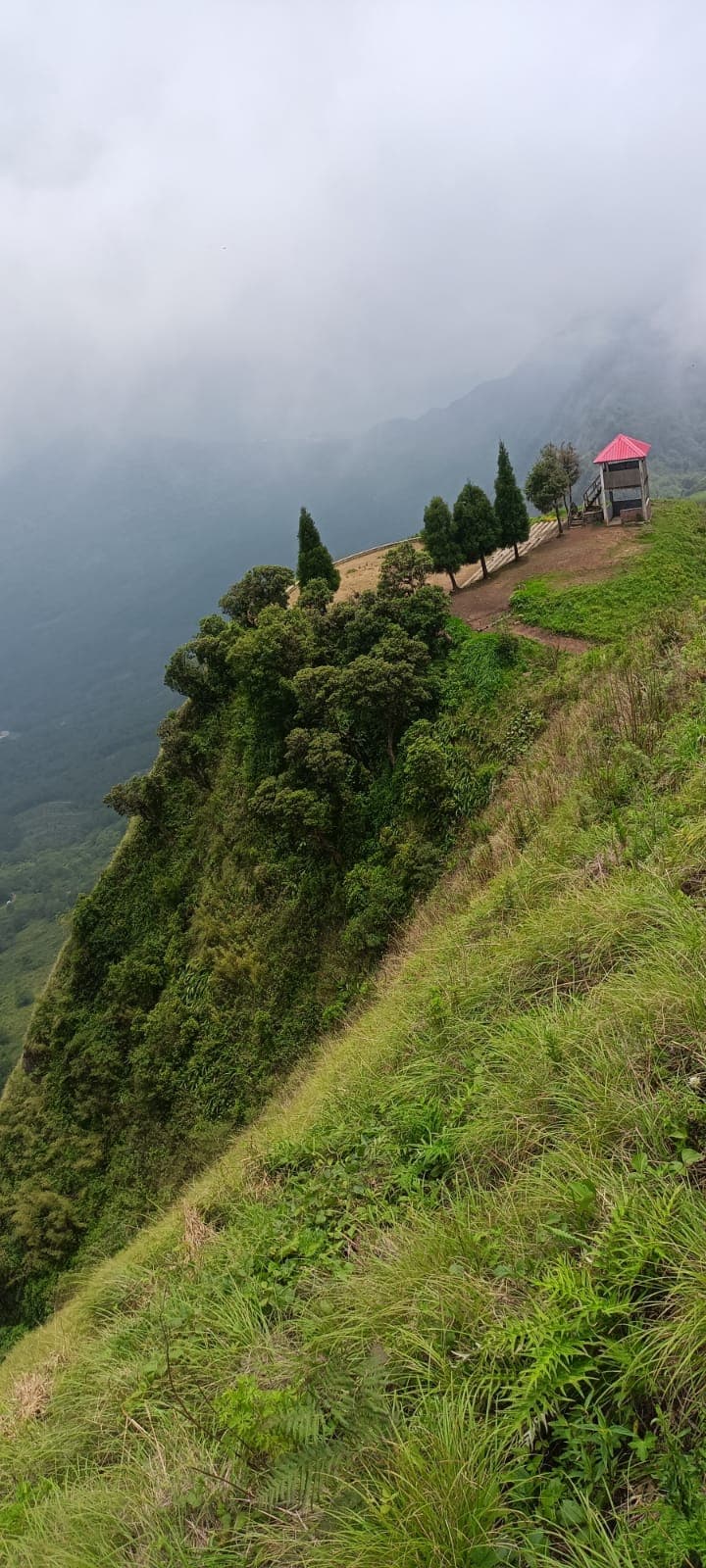 Green Kapamodzu ridge and small shelters disappearing into cloud